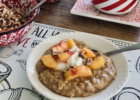 bowl of cooked oats topped with plain Greek yogurt, fresh peaches and toasted pecans, made with Nature's yoke eggs